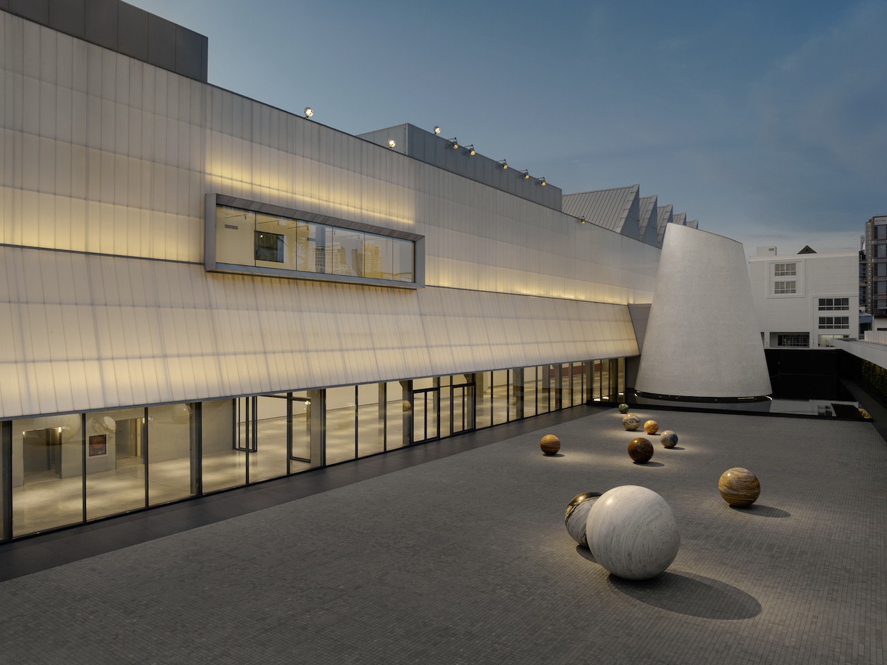 Dib Bangkok’s inaugural exhibition, “(I)nvisible Presence” running until 3 August 2026 is a solid test of the museum’s spaces; in the courtyard, Alicja Kwade’s Pars pro Toto (2020) installation of 11 monumental stone globes gives physicality to the enigma of planetary systems.  